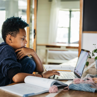 Young student doing homework on his laptop