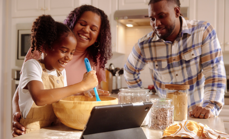 A father and mother both are doing some fun while making the food with his child.