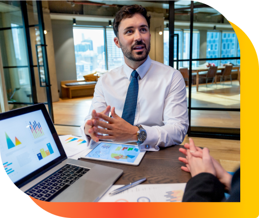 A business meeting with laptops, documents, and charts on a desk in an office with city view.